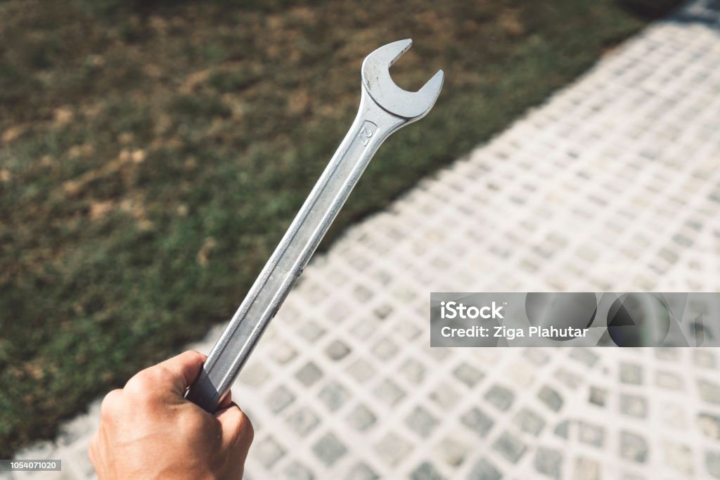 Worker holding a combination ratcheting wrench A picture of a man holding a combination ratcheting wrench in his hand, being outside, using home-tools, hand tools in the use, strong man holding a combination ratcheting wrench. Nut - Fastener Stock Photo