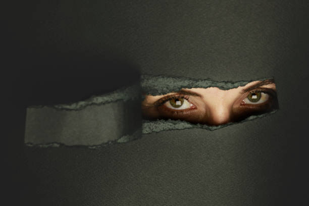 istock Girl watches through a hole in cardboard 1054077624