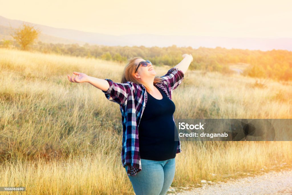 Young woman enjoying nature Pregnant woman with raised arms in nature smiling Women Stock Photo