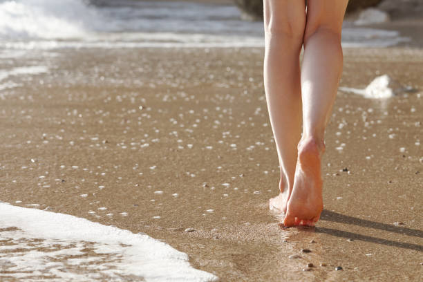 istock Woman walking on a sandy beach, feet close up view 1054084692