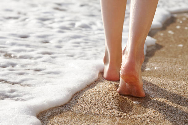 istock Woman walking on a sandy beach, feet close up view 1054084704