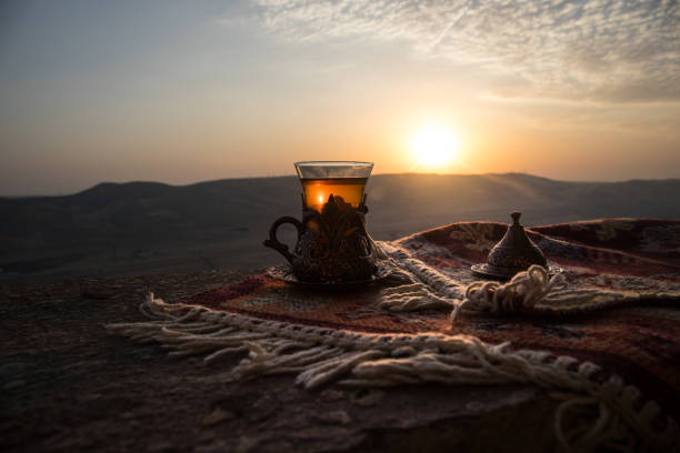 istock Arabian tea in glass on a eastern carpet. Eastern tea concept. Armudu traditional cup. Sunset background. Selective focus 1054092332