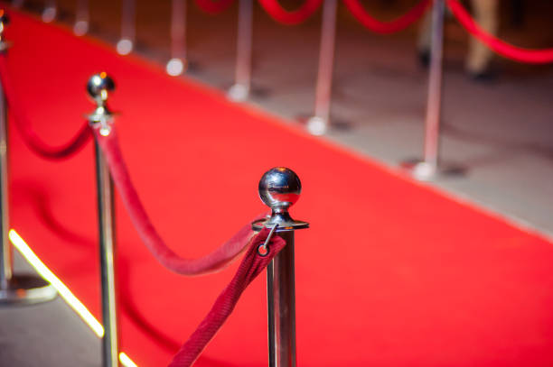istock Long red carpet between rope barriers on entrance. 1054152070