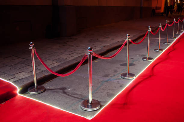 istock Long red carpet between rope barriers on entrance. 1054152240
