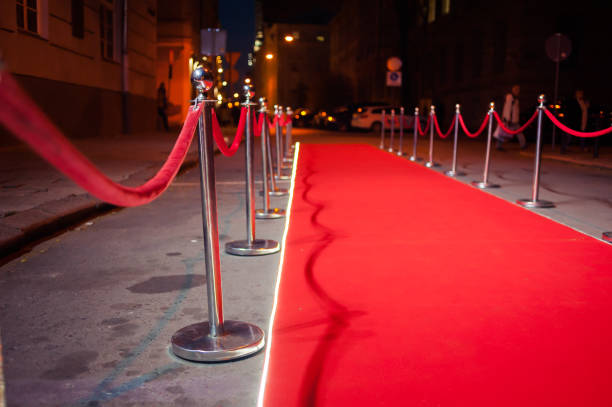 istock Long red carpet between rope barriers on entrance. 1054152402