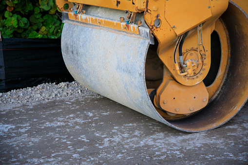 Asphalt compactor roller on some unpaved gravel surface.