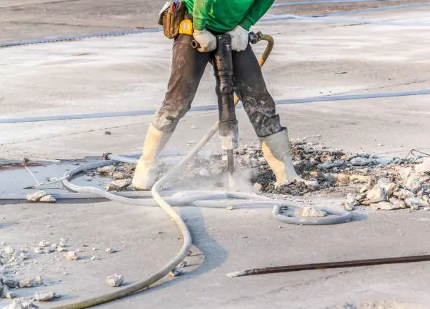 worker of road construction drilling cement ground