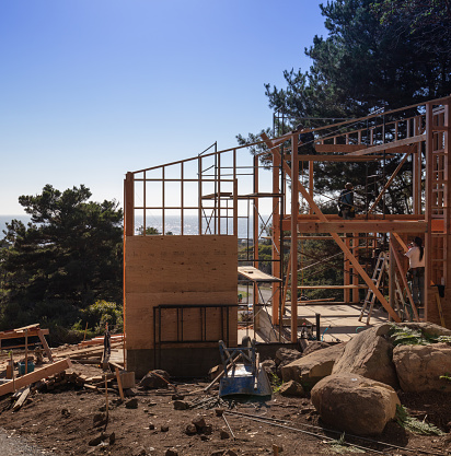 THE SEA RANCH, CALIFORNIA - October 10, 2018: Men building a home by the ocean at The Sea Ranch, a private community in Sonoma County, Northern California. The house is in the initial framing phase of construction.