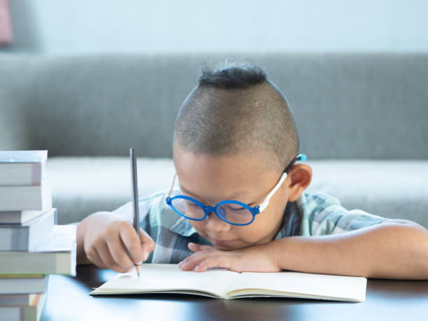istock Cute asian boy write homework at home. education concept 1054195236