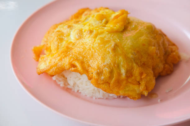 Thai style pork omelette on hot steamed rice on pink dish