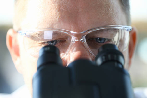 male scientist looking through binocular - microscope view imagens e fotografias de stock