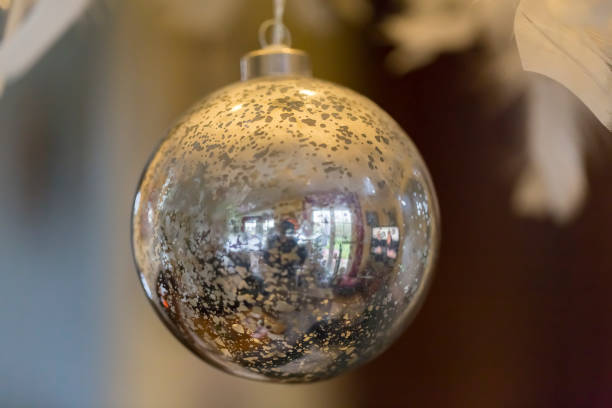 istock silver huge Christmas ball hanging on tree branches at the Christmas fair. it reflected Christmas lights 1054219552
