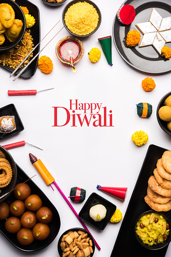 Happy Diwali Greeting Card made using sweets, or fire crackers or Diya or flowers, selective focus