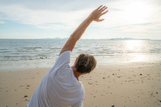 istock Sportive young man stretching on beach after morning jogging 1054222524