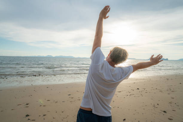 istock Sportive young man stretching on beach after morning jogging 1054222826