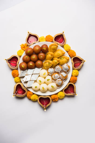 Diwali Rangoli made using Diya/oil lamp, flowers and plate full of Gulab Jamun, Rasgulla, kaju katli, morichoor / Bundi Laddu, Gujiya or Karanji Diwali Rangoli made using Diya/oil lamp, flowers and plate full of Gulab Jamun, Rasgulla, kaju katli, morichoor / Bundi Laddu, Gujiya or Karanji mithai stock pictures, royalty-free photos & images