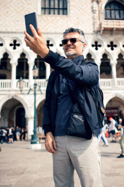 istock Senior bearded man smiling while taking selfie picture with mobile phone 1054226008