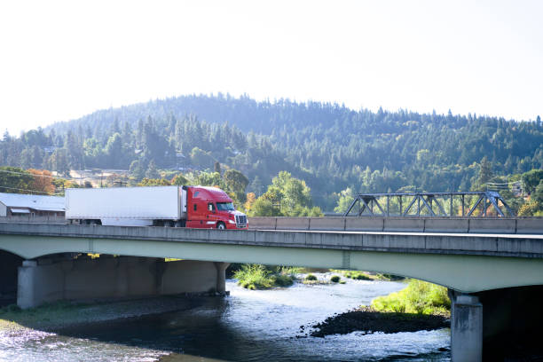 현대 큰 장비 세미 트럭 세미 트레일러 산 강을 건너는 다리에 이동 - semi truck truck highway red 뉴스 사진 이미지
