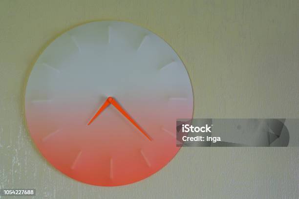 Round Orange Clock Hanging On Light Yellow Wall Stock Photo - Download Image Now - Alarm, Circle, Clock