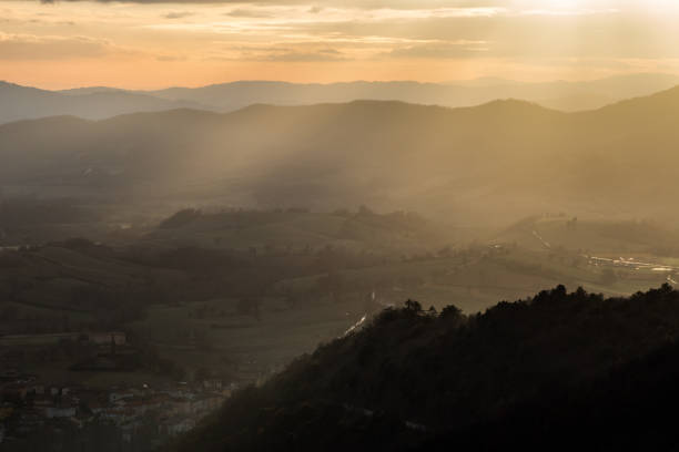 istock Sunrays coming over a valley in Umbria (Italy) with some plants on a hill in the foreground 1054230774
