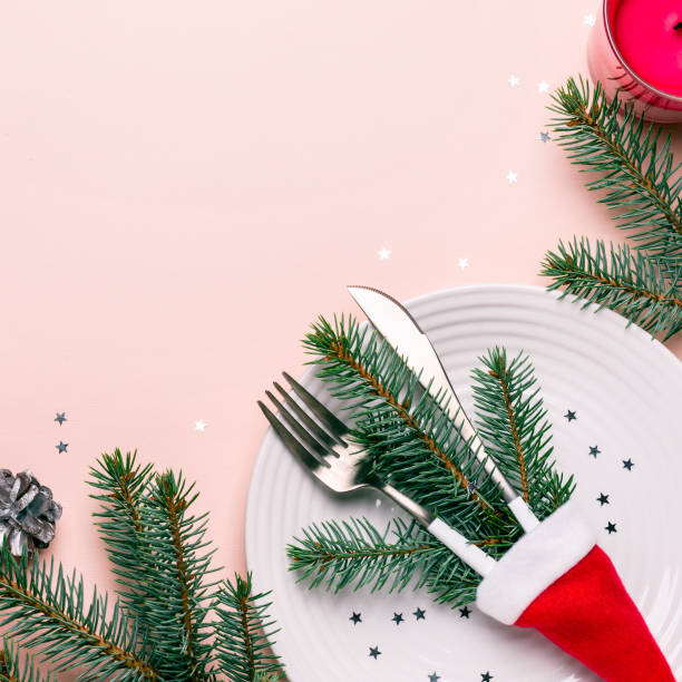 istock Fir branches and cutlery in Santa hat on pink background. Christmas table setting 1054241320