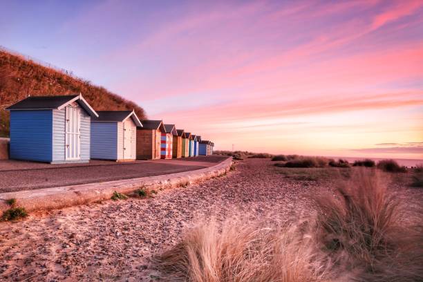 пляжные хижины рано утром на пляже pakefield в lowestoft, саффолк в англии. - east anglia фотографии стоковые фото и изображения