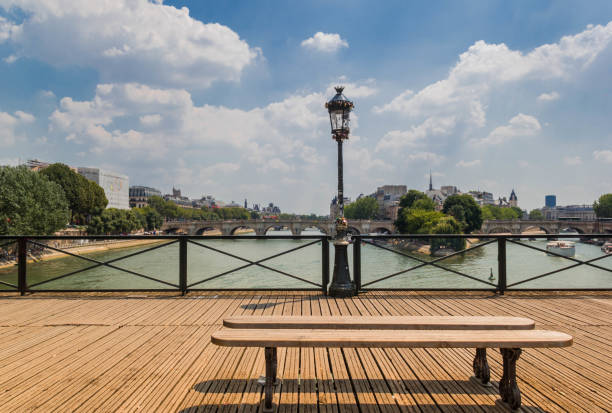 The wooden bench on Pont des Arts Bridge in Paris with view of Pont Neuf and Cite Island in the middle of Seine River