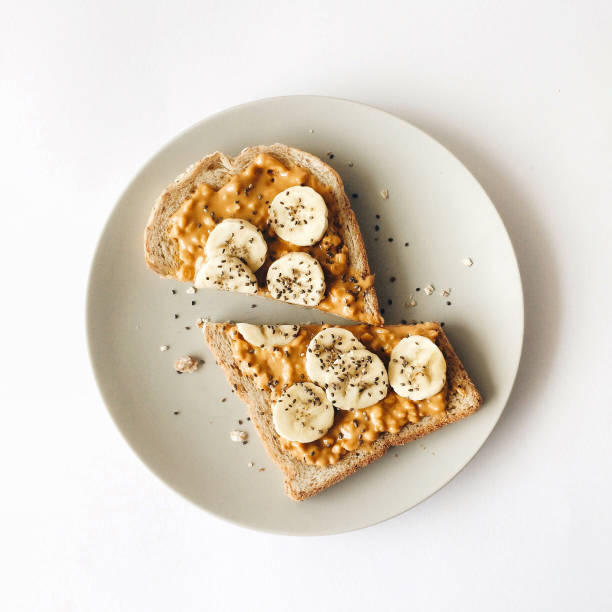 mantequilla de maní con tostada de plátano para el desayuno - grano entero fotos fotografías e imágenes de stock