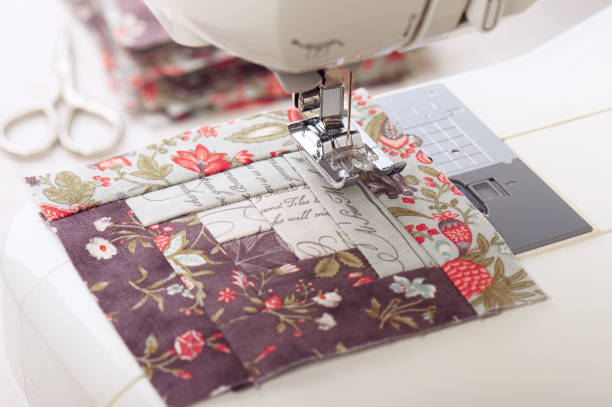 istock Patchwork log cabin blocks on electric sewing machine, stack of blocks, sewing accessories 1054297576