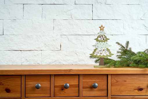 Christmas decoration with twigs of spruce and wooden Christmas tree on an old shelf on the background of a white brick wall