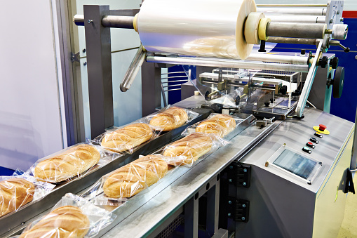 Packing machine with a roll of film for loaves of bread