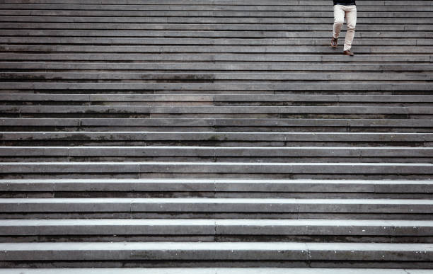 istock Anonymous person walking down on the stairs 1054304570