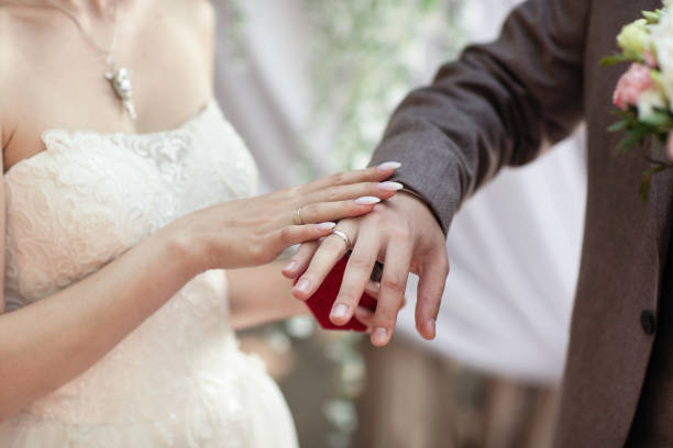 istock Dressing wedding rings. Arms. No faces visible 1054304842