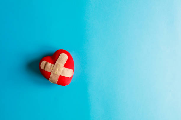 istock Band-aid covering a heart on a blue paper background 1054316936