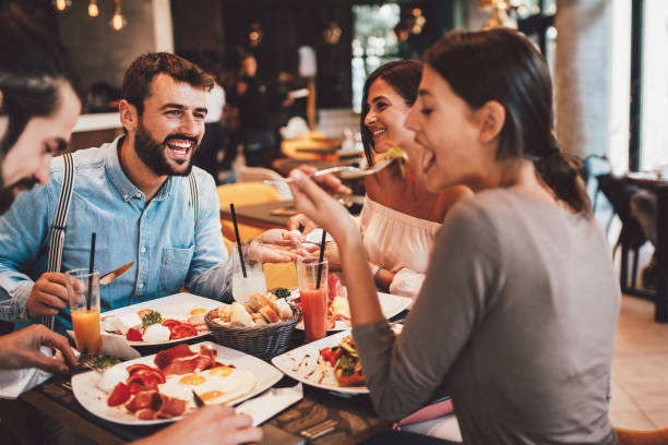 Groupe d’amis heureux prenant son petit déjeuner dans le restaurant - Photo