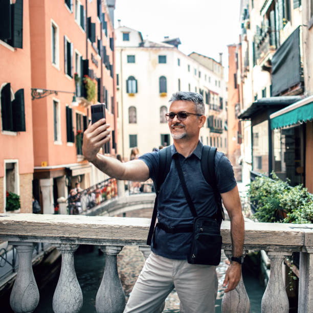 istock Tourist smiling while taking selfie picture with mobile phone 1054319454