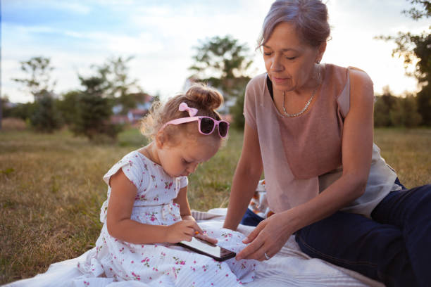 istock Grandmother and granddaughter using tablet in nature 1054334236