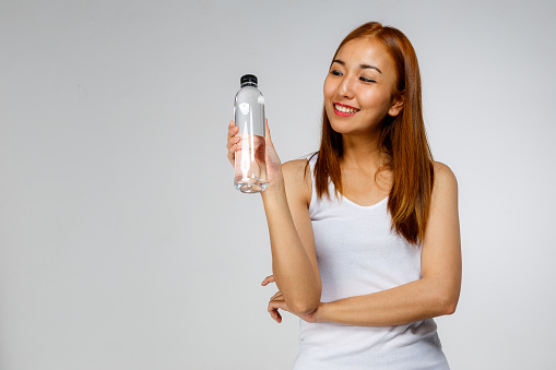Young Asian woman with water bottle on white background