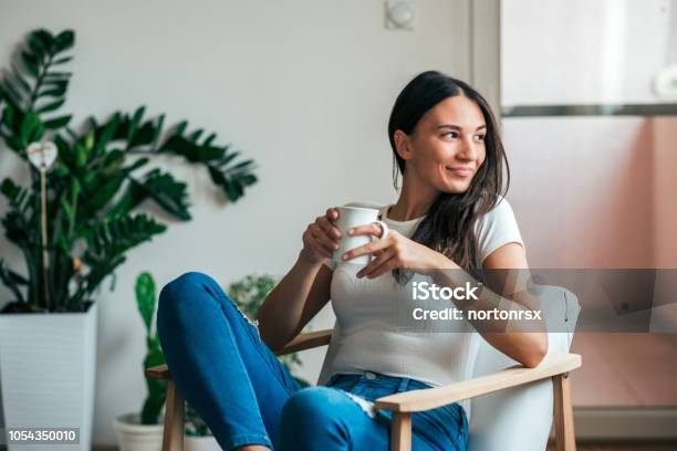 Beautiful Young Woman Drinking Tea At Home Looking Away Stock Photo - Download Image Now