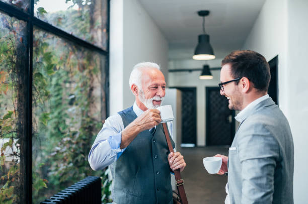 smiling senior and young business men on a coffee break. - business business person ceo coffee imagens e fotografias de stock