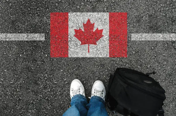 Photo of a man with a shoes is standing next to flag of Canada