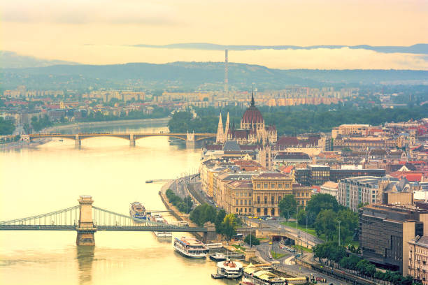 Budapest downtown and Danube river River, bridges and Budapest riverfront with Parliament building in yellow haze danube river stock pictures, royalty-free photos & images