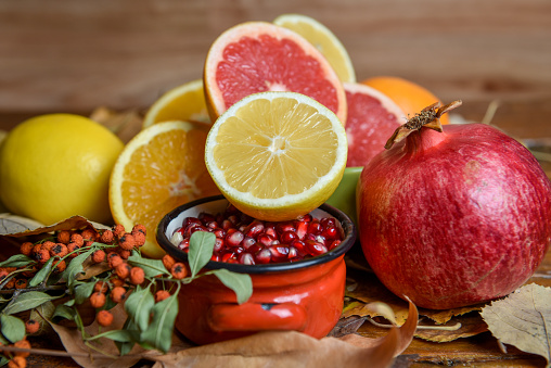 Mixture slices of healthy tropical fruits, lemon, orange, grapefruit, pomegranate, pomegranate seed. Vintage look. Antioxidant healthy fruits. Autumn leaf