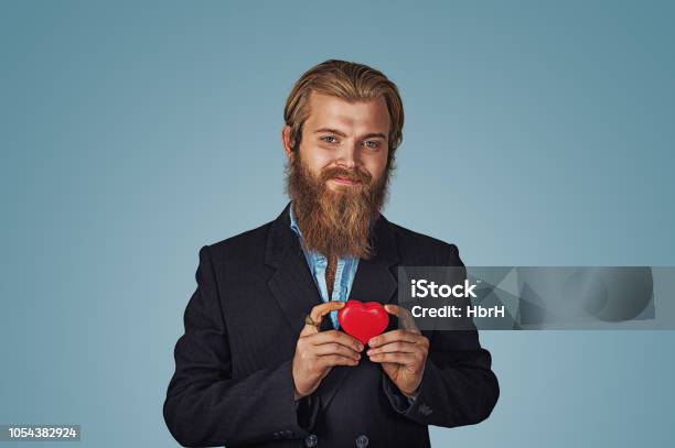 Hombre De Chaqueta Negra Y Camisa Azul Permanente Y Caja De Regalo Roja En Forma De Corazón Grande Foto de stock y más banco de imágenes de Bigote