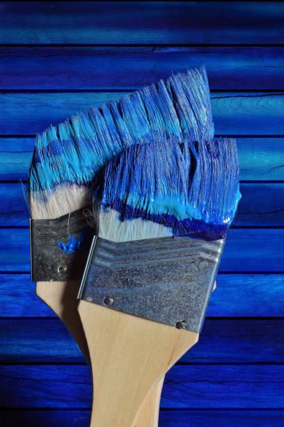istock Close-Up Of Paintbrush Against Blue Wall 1054397842