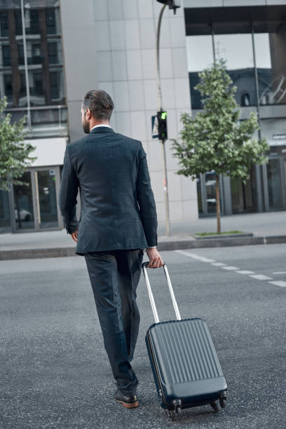 istock Full length rear view of young man with a suitcase 1054400356