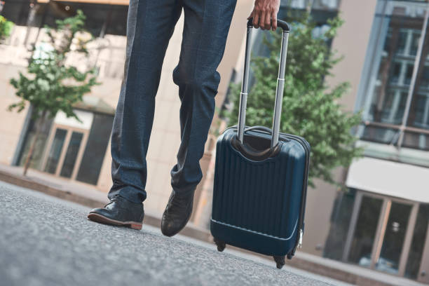istock A young businessman scrosses road with suitcase, cropped view 1054400370