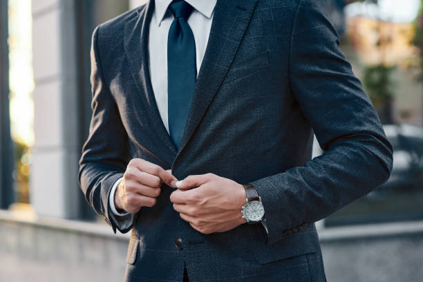 istock A young businessman fastens a suit jacket. He has on his hands an expensive watch. 1054400482