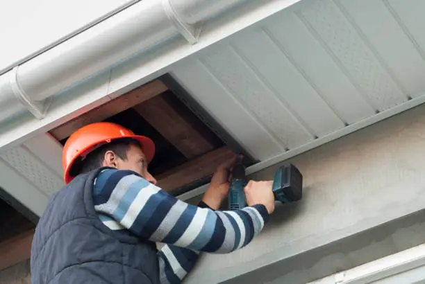 construction worker mounts a soffit on the roof eaves