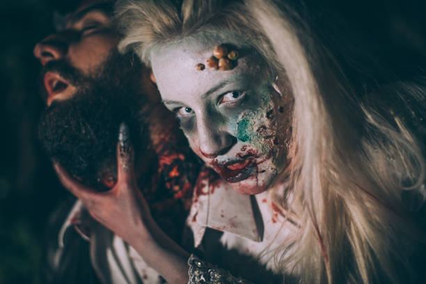 Woman masked as halloween witch Man and woman, she masked herself in a scary witch for halloween, attacking a man. male vampire biting his victim stock pictures, royalty-free photos & images